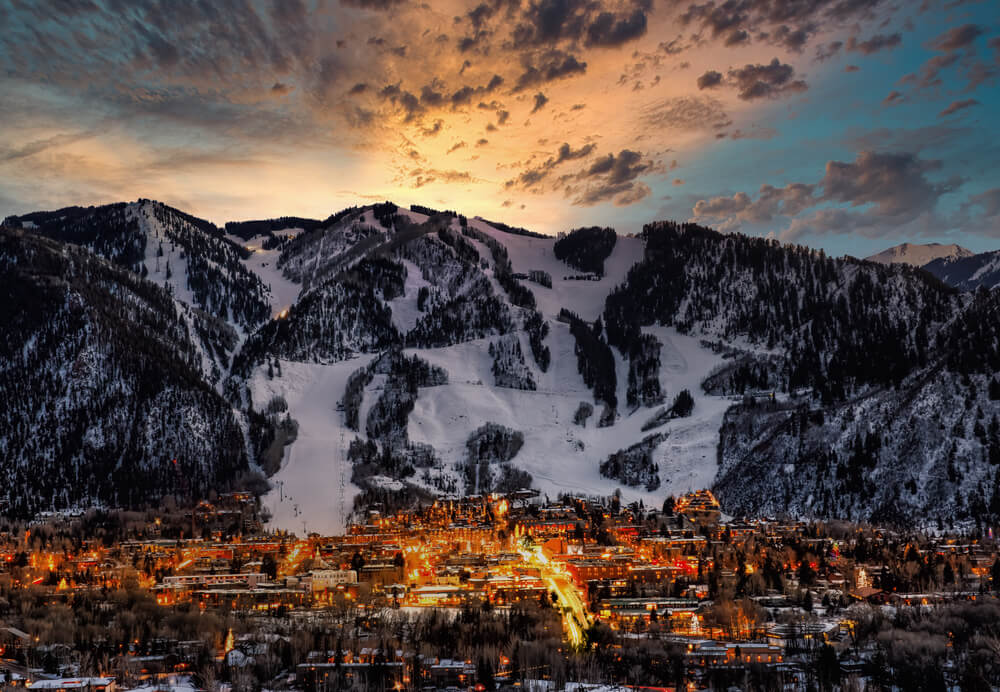 glow of aspen resort town in the snow at night around sunrise with the lights coming on in the resort town