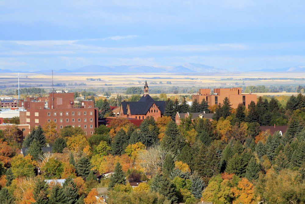 Bozeman in the early fall, orange-pink college buildings surrounded by green and orange trees.