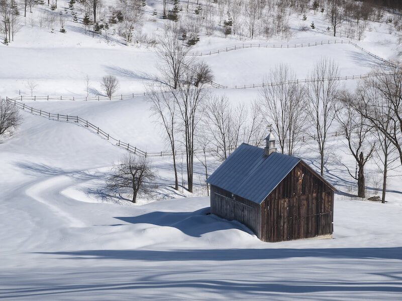 snow covered barn or house in vermont in winter around christmastime in the usa