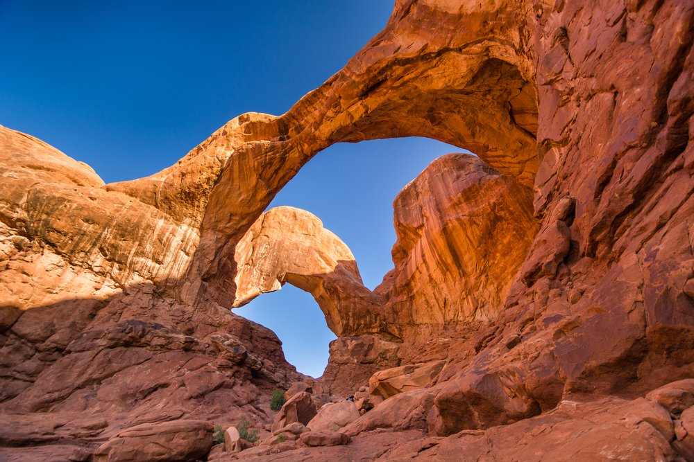 low angle shot looking up to the double arch off the trail in moab.