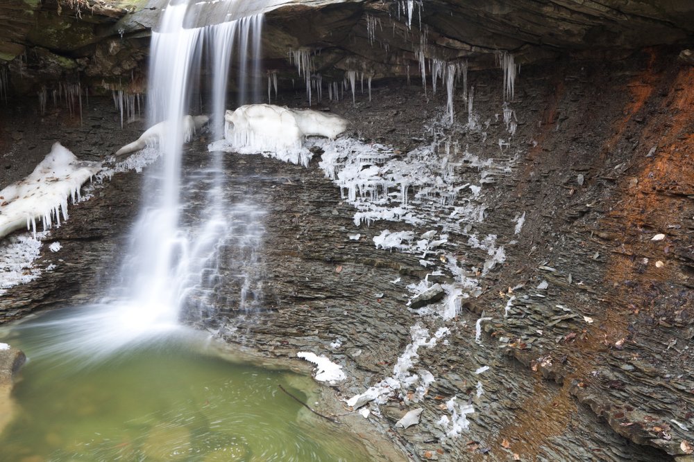 Snow starting to form on an Ohio waterfall and into a pool of pale green water