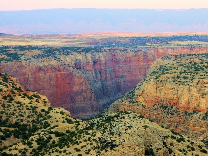 A Grand Canyon looking landscape with rocks with red, orange, and yellow tones creating a large canyon.