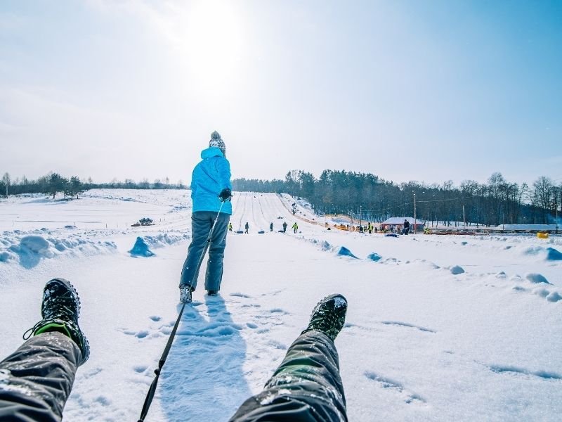 A view of someone's feet as a woman pulls their tube forward in Jackson Hole in winter