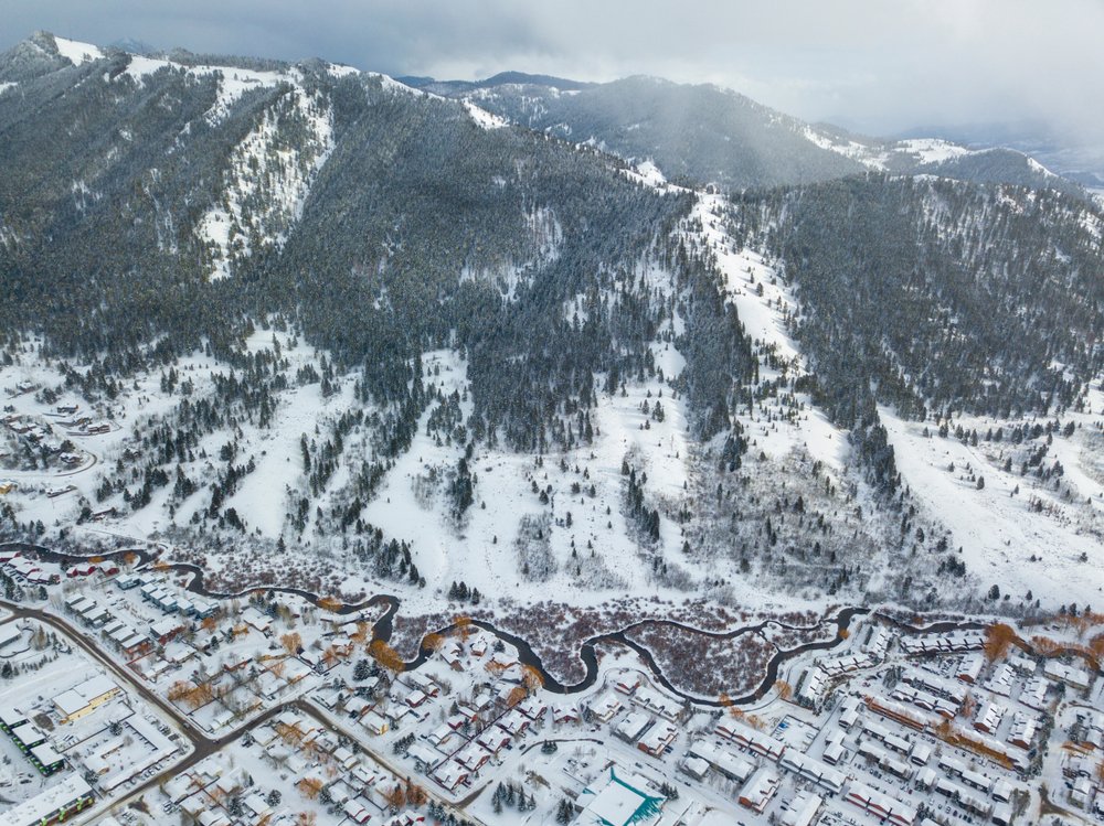 An aerial photo taken with a drone of Jackson Hole town with a river winding through it and mountains on the edge of town