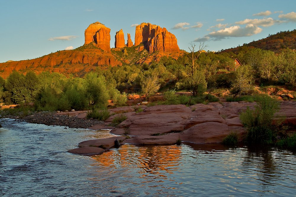 The traditional red rocks of Sedona with a stream in the foreground reflecting the red rocks