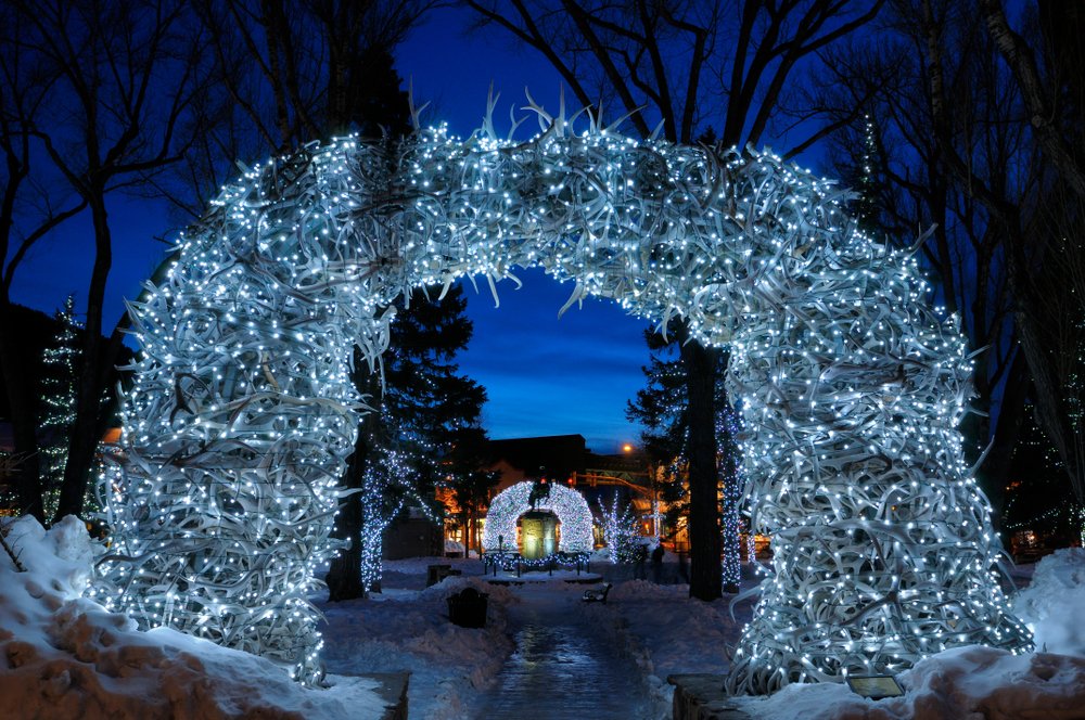 The famous "antler arch" in Jackson in winter styling with lots of blueish Christmas lights on it, making it shine a pale blue color