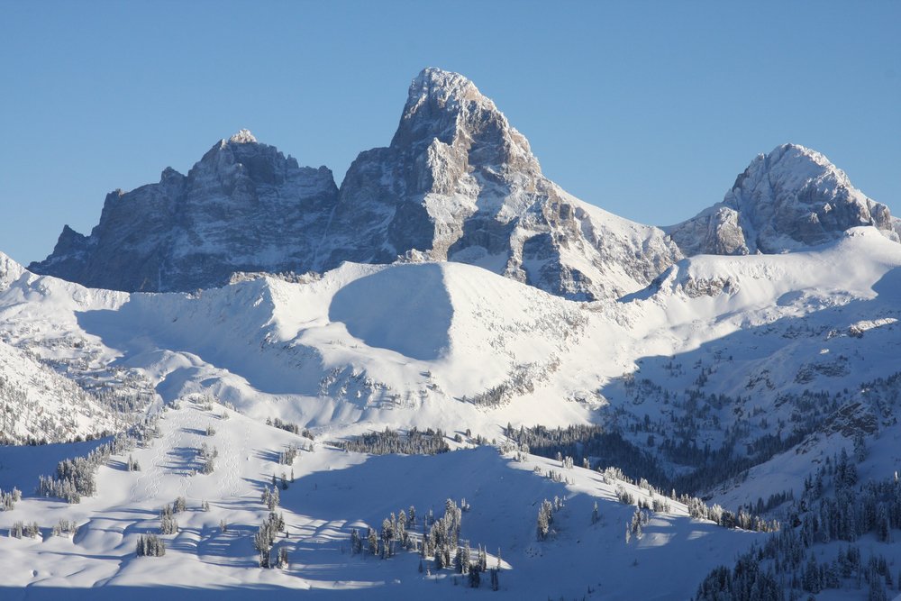 A classic view of Grand Teton National Park in winter: peaks covered in snow with blue skies