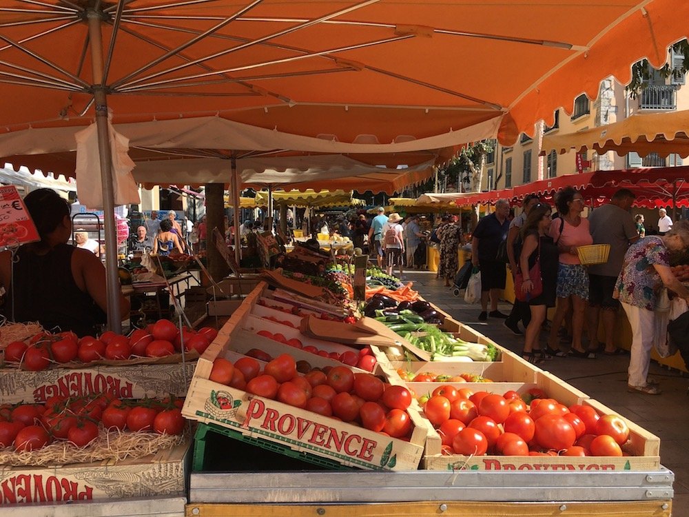 produce at a market with people perusing the fresh fruits and vegetables in the summer