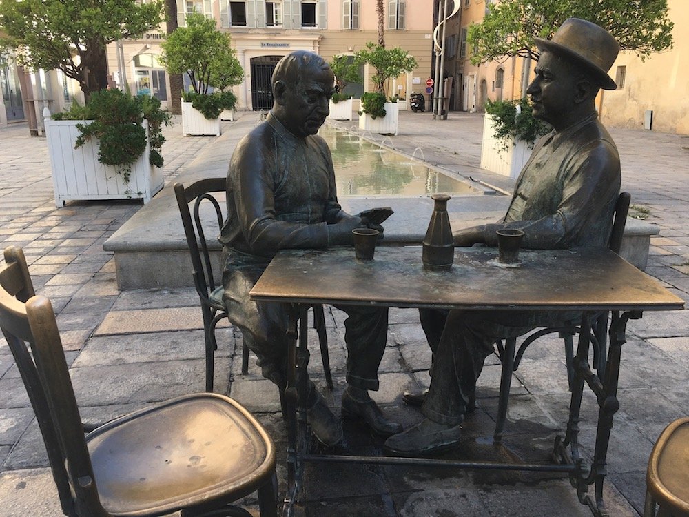 statue of two people sitting at a table drinking