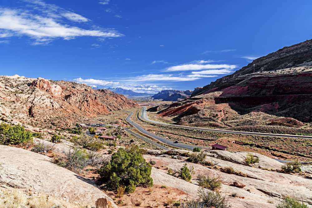 Highway 70 going through Moab with red rocks and desert landscape around it.