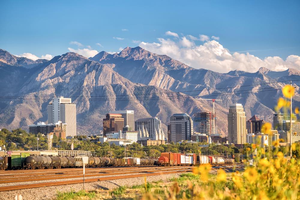 A view of the skyline of Salt Lake City with enormous mountains towering over the city.