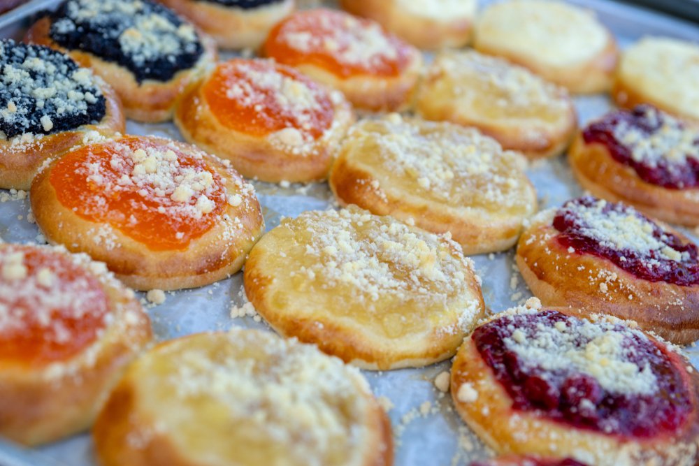 Four different colorful kolache Czech pastries, with black, orange, yellow, and red jams, a great way to start a day in Prague.