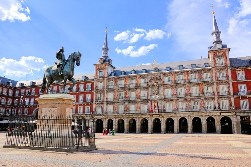 A man on a horse statue and red buildings in the background 