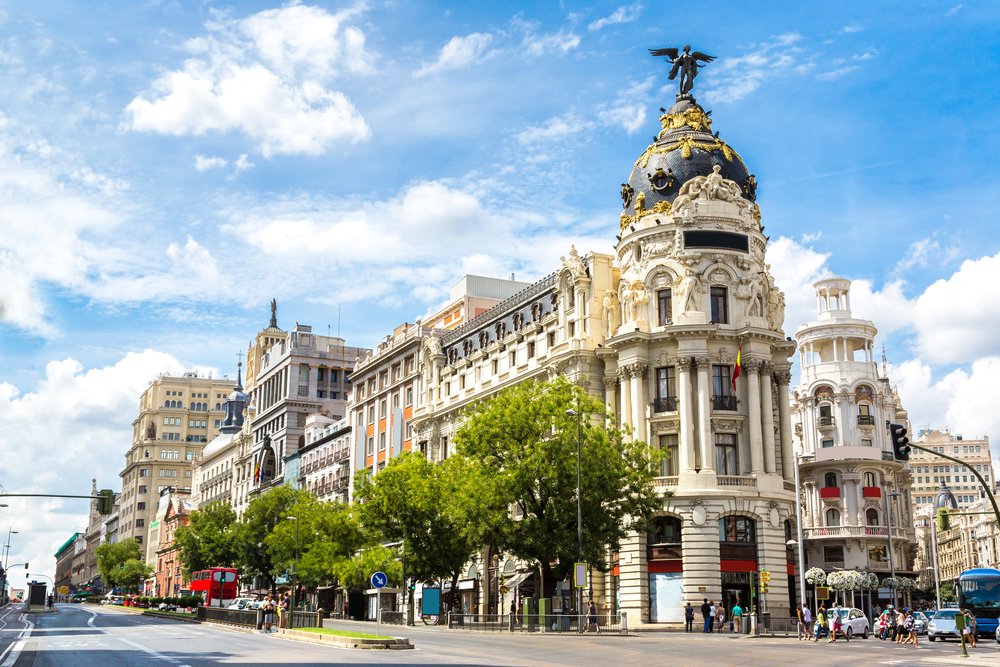 A grand European boulevard with a building with an angel on top of the roof