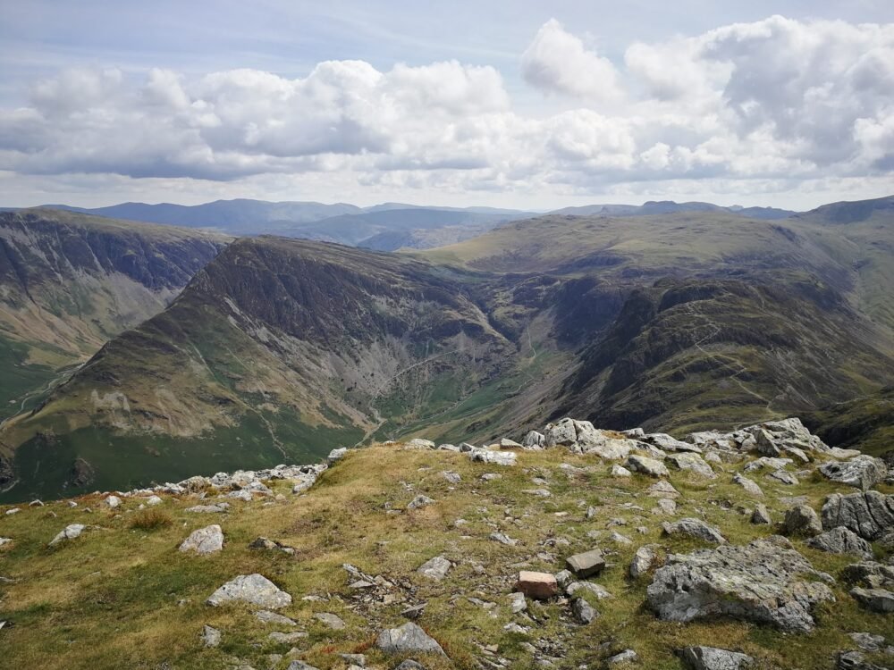 View of rocky and grassy summit of a mountain the Lakes District, on a partly cloudy day.