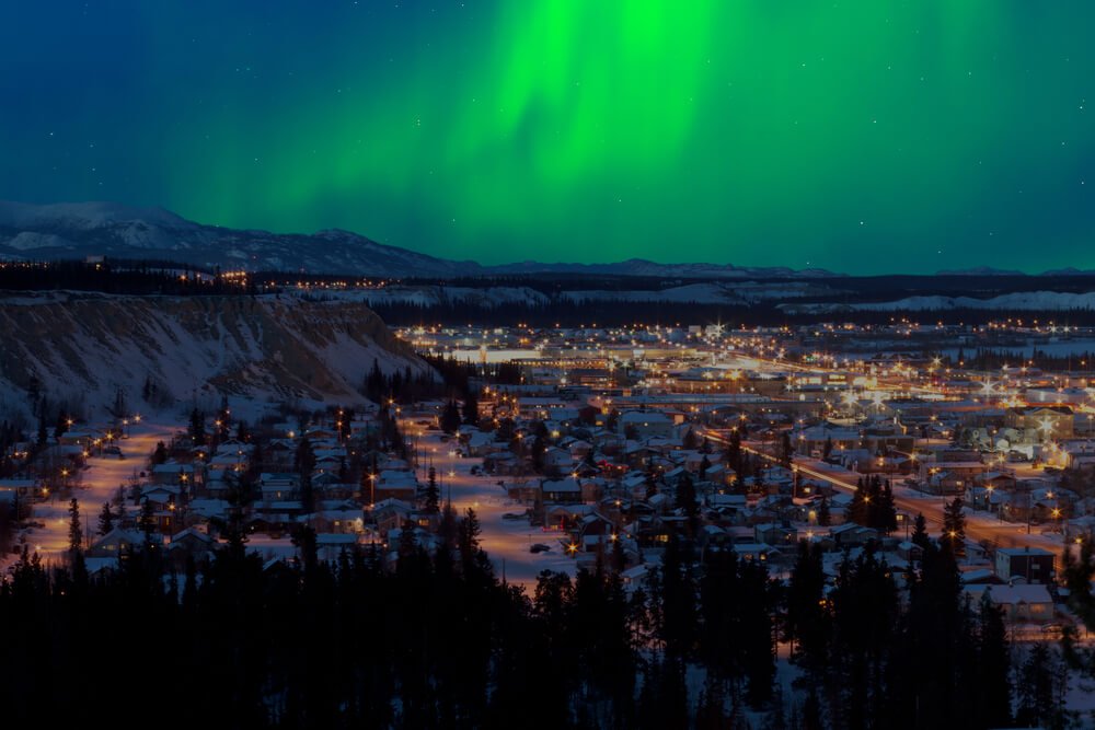 Green Northern lights above the lights of the town of Whitehorse, Yukon in Canada along the AlCan Highway