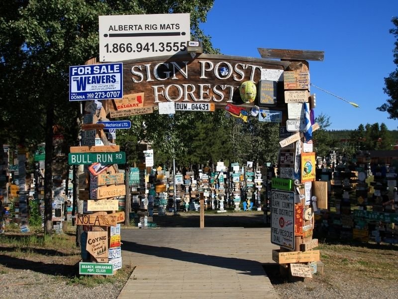 Sign which reads "Sign Post Forest" surrounded by lots of signs from all over the world along the AlCan Highway