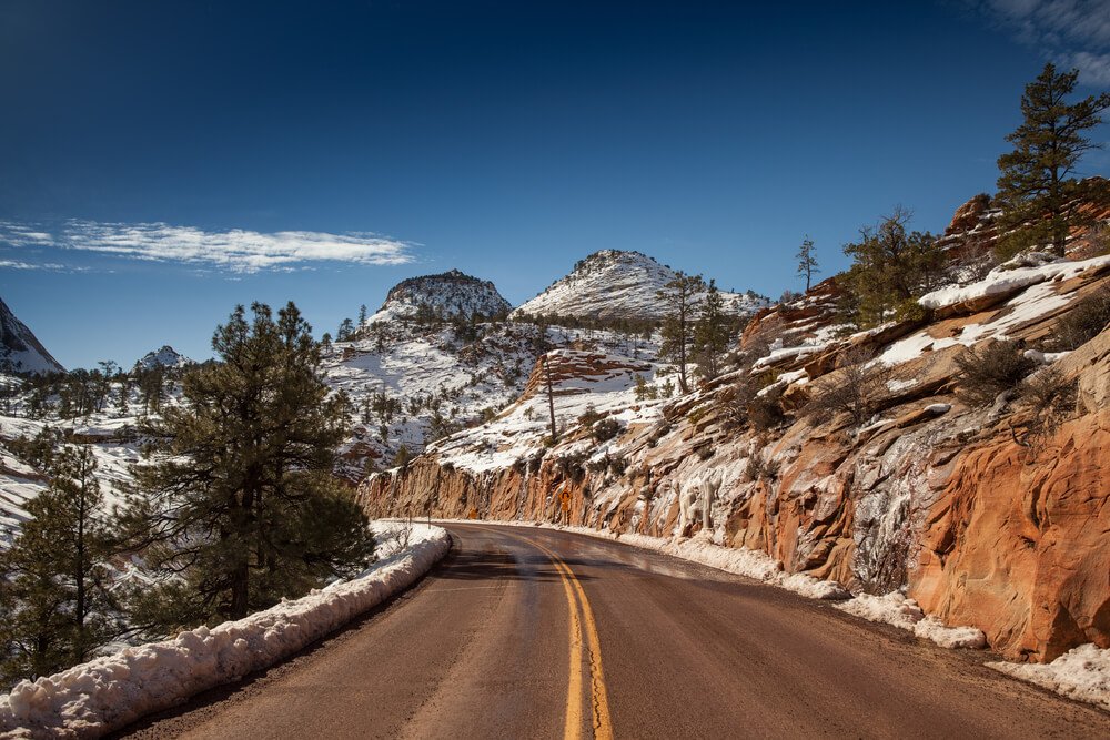 Curve in the road going through a snow covered section of Zion National Park in the winter on a sunny day