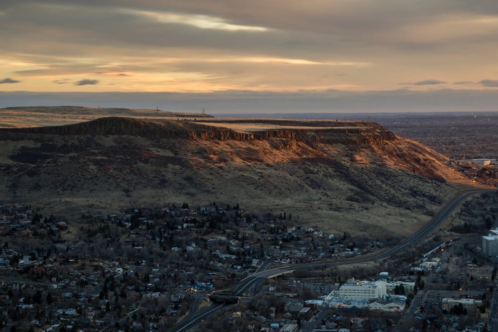View of North Table Mountain, seen at sunset, surrounded by a small town, a mesa with a flat top.
