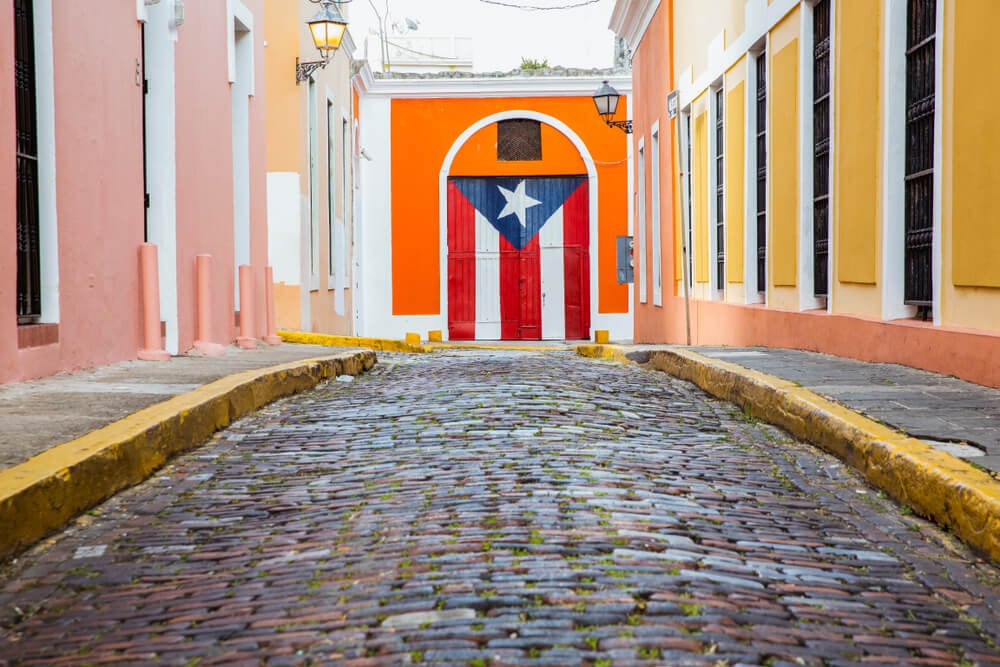a mural of the puerto rican flag surrounded by colorful walls and cobblestones