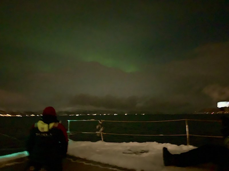 A blurry photo of the Northern lights appearing over the fjord on a sailing cruise near Tromso