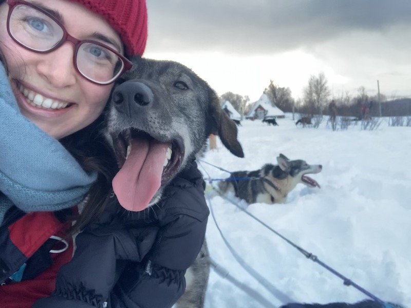 Allison taking a selfie with a very happy looking black dog with a white muzzle and open mouth