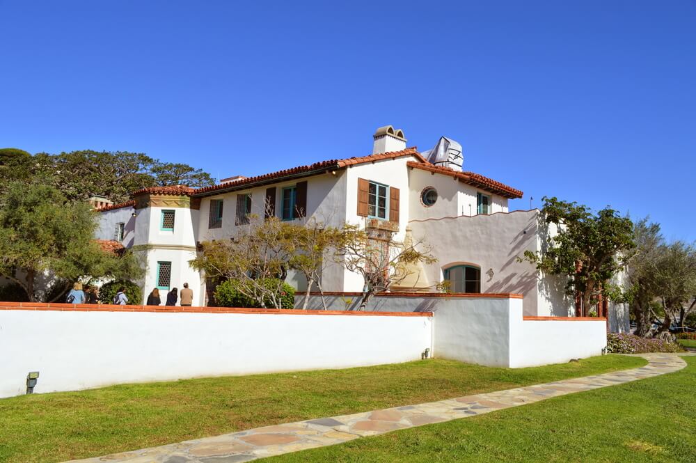 White stucco-style house with lots of Spanish colonial style architectural detailing on a sunny day on a Malibu California day trip