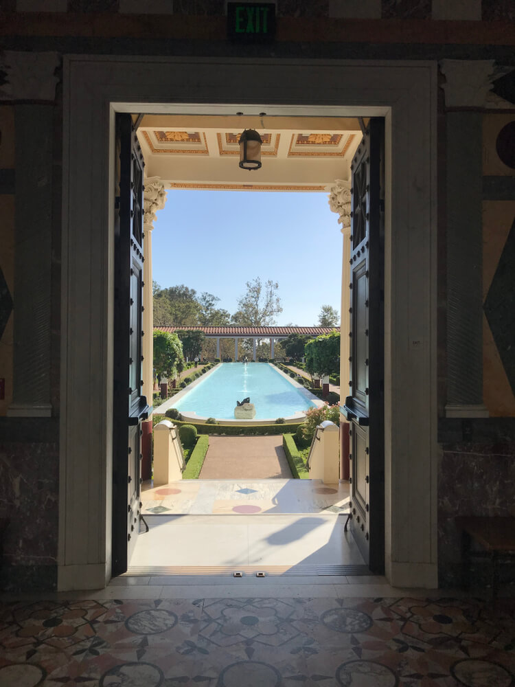 Vertical photo showing the pool of the Getty Villa as seen through an open door