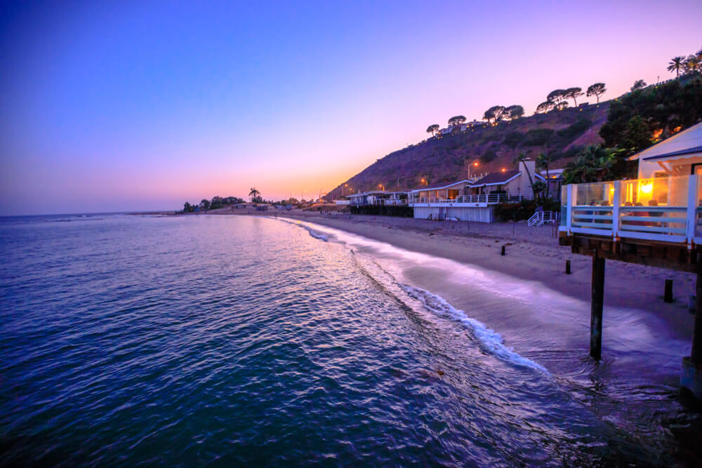 Scenic coastal landscape with Santa Monica Mountains and Surfrider Beach at dusk illuminated by night. 