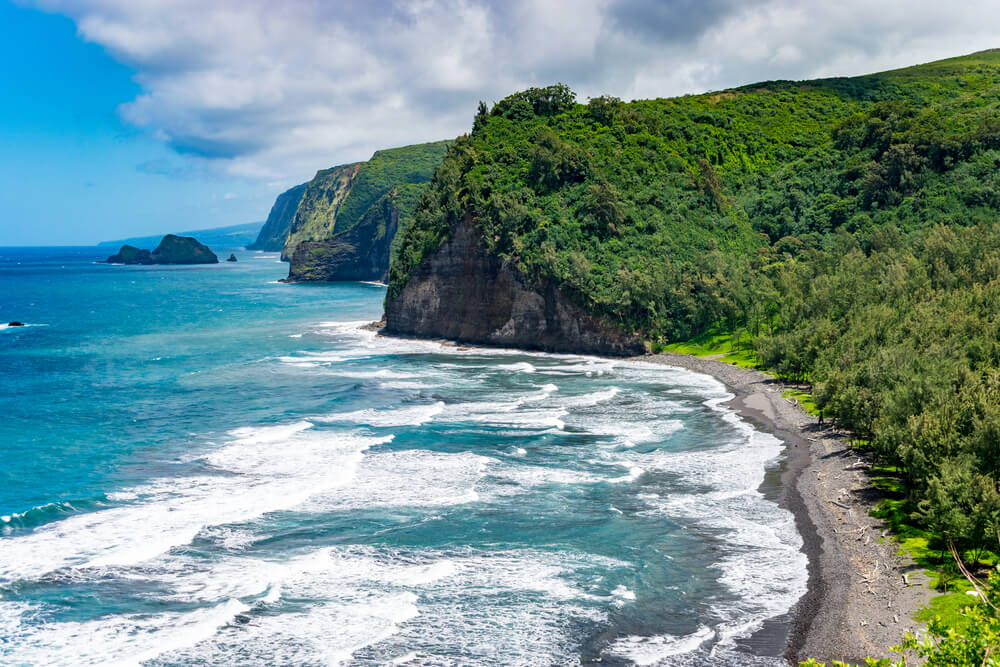 the landscapes around polulu valley with green cliffs, beach, and ocean