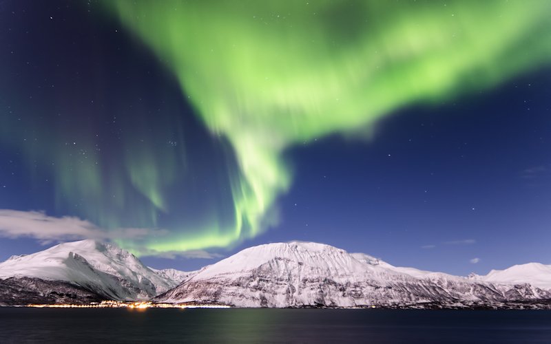 northern lights rippling over the fjords in norway