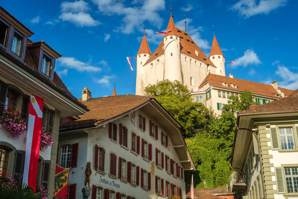 The enormous castle of Thun looming over the cute village on a sunny day.