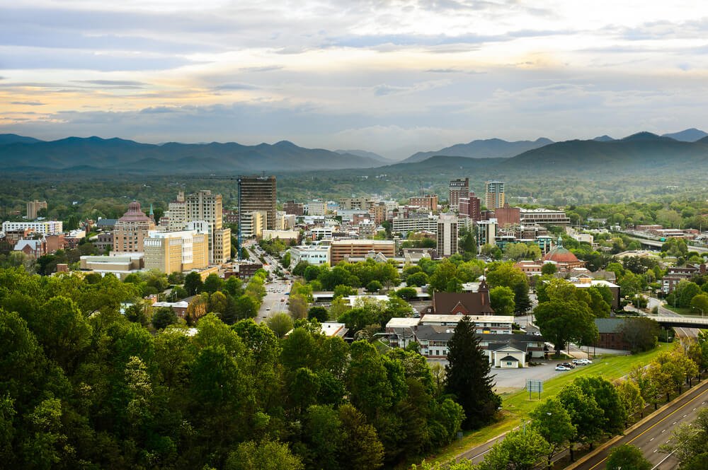 skyline of asheville nc buildings poking up between hills and trees