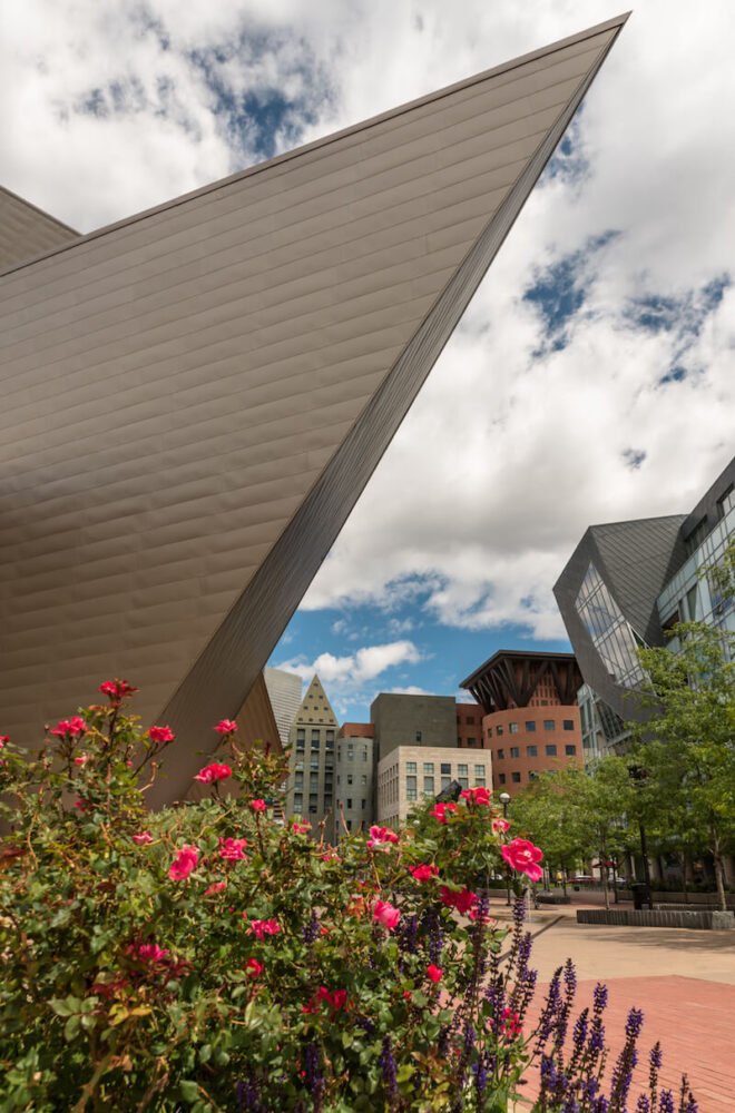 A photo of flowers in front of The Denver Art Museum with Downtown Denver in the background