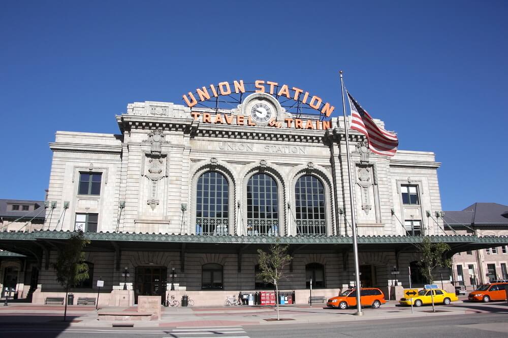 The exterior of Denver Union Station with cars and taxis in front of it