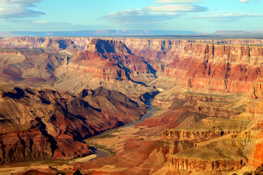 Orange and red rocks of the Grand canyon from a vista point with a view of the Colorado River winding below