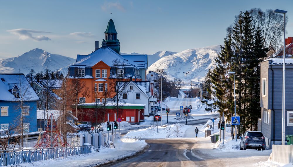 very snowy landscape in tromso in the winter with lots of snow accumulation on the buildings in the center of town