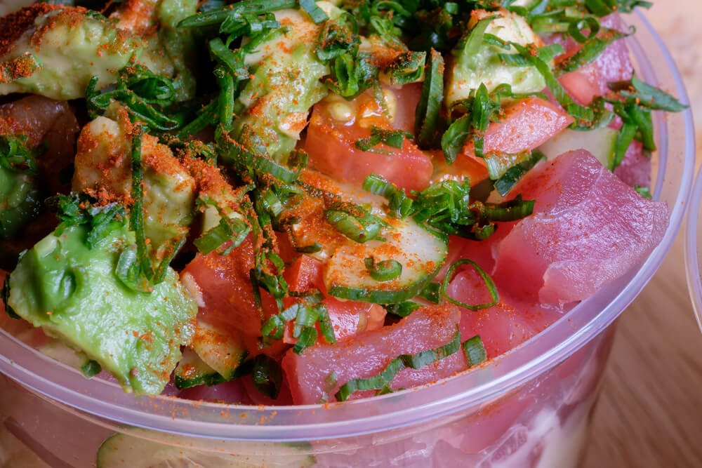 Close up of a bowl of tuna poke with avocado, cucumber, scallions and chili