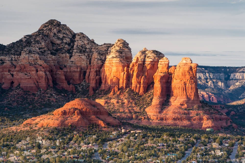 Falling light of the sunrise or sunset casting a glow on the red rocks of Sedona overlooking the Verde Valley with green trees in the valley
