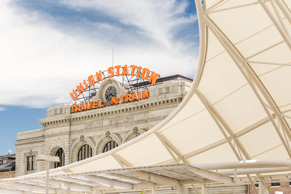 Light rail station in front of Union Station in Denver. Text on building reads "Union Station Travel by Train"