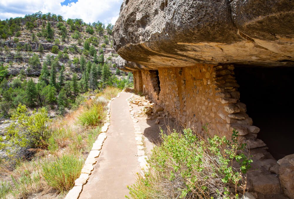 Native American ruins in Walnut Canyon National Monument, Arizona, with a hiking path going past them.
