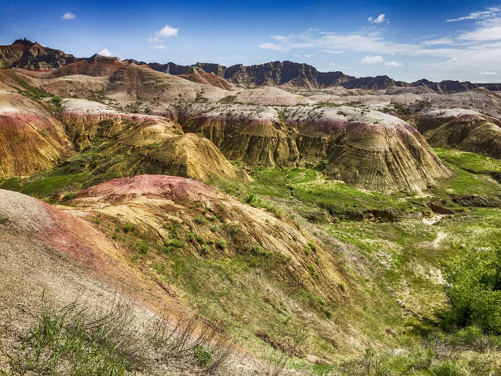 Beautiful formations within Badlands National Park with green flora and red and earth toned rock