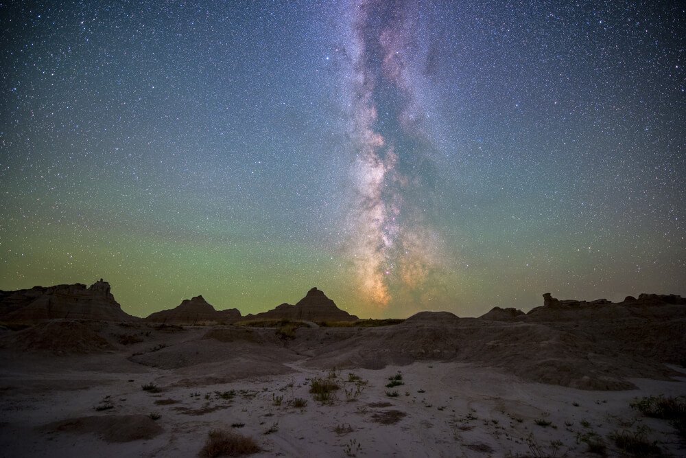 The colors of the Milky Way stretching up over the horizon in Badlands National Park, South Dakota