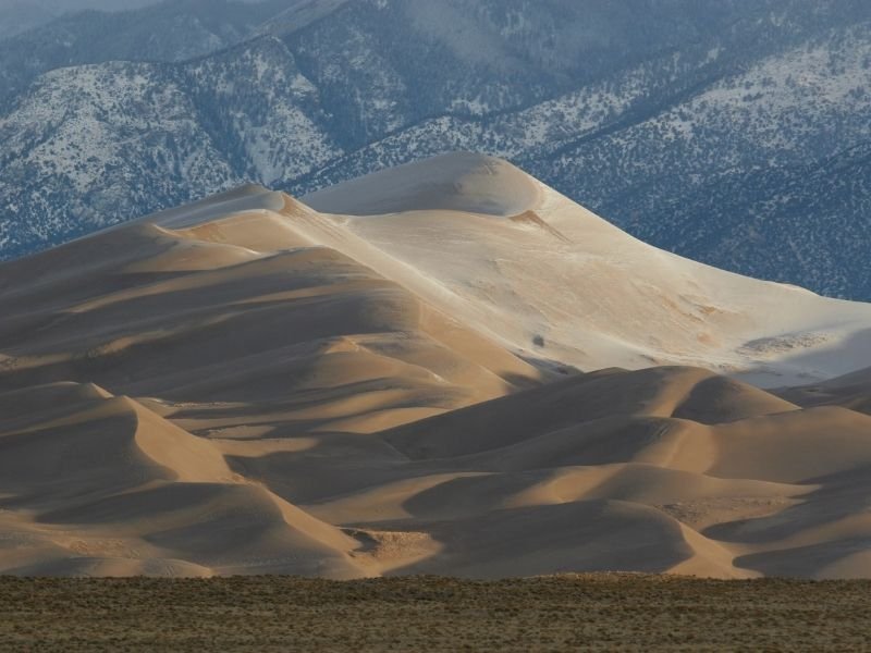 layers of beautiful sand dunes stacking against each other in the early morning light in colorado