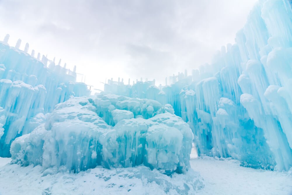 The beautiful ice formations in a brilliant turquoise pale blue color against a cloudy winter sky