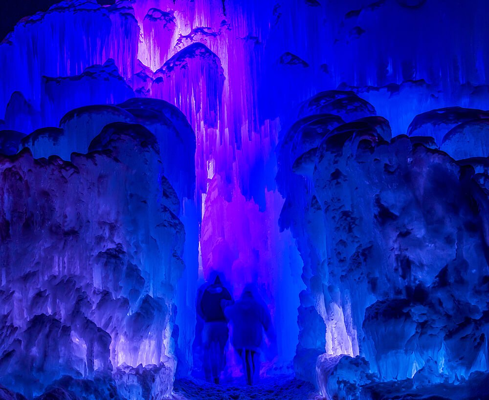 Colorful ice castle lit up at night with bright colors of purple and pink