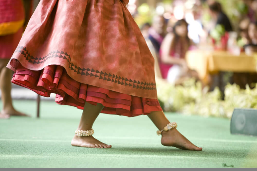 Close up of a hula dancer on a stage, focus on the her feet