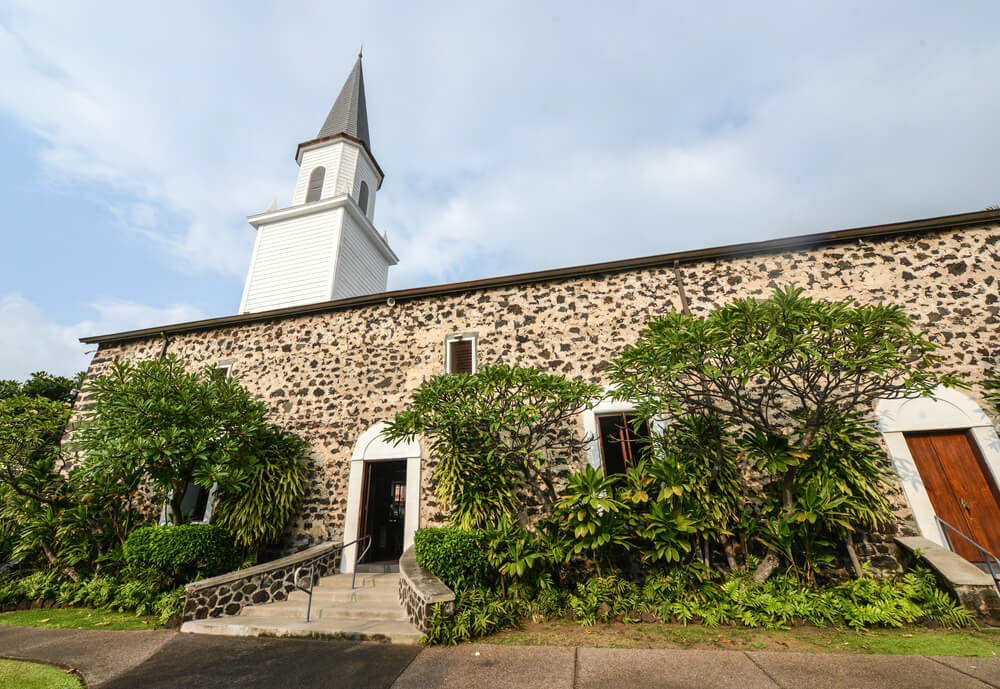 stone church with hawaiian foliage in front and a tall steeple