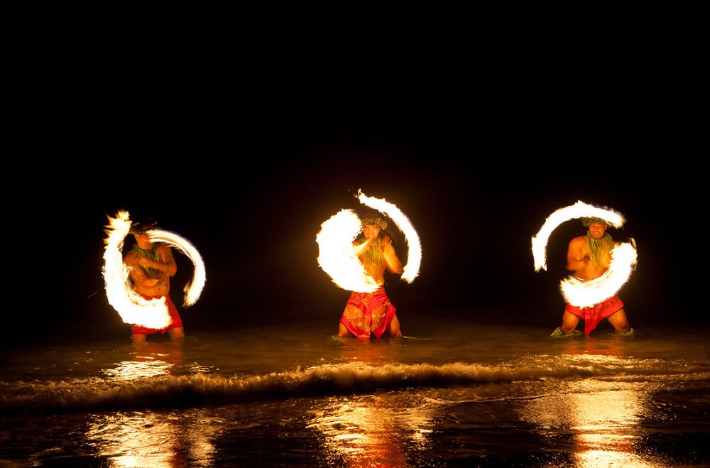 three men spinning fire at a hawaii luau