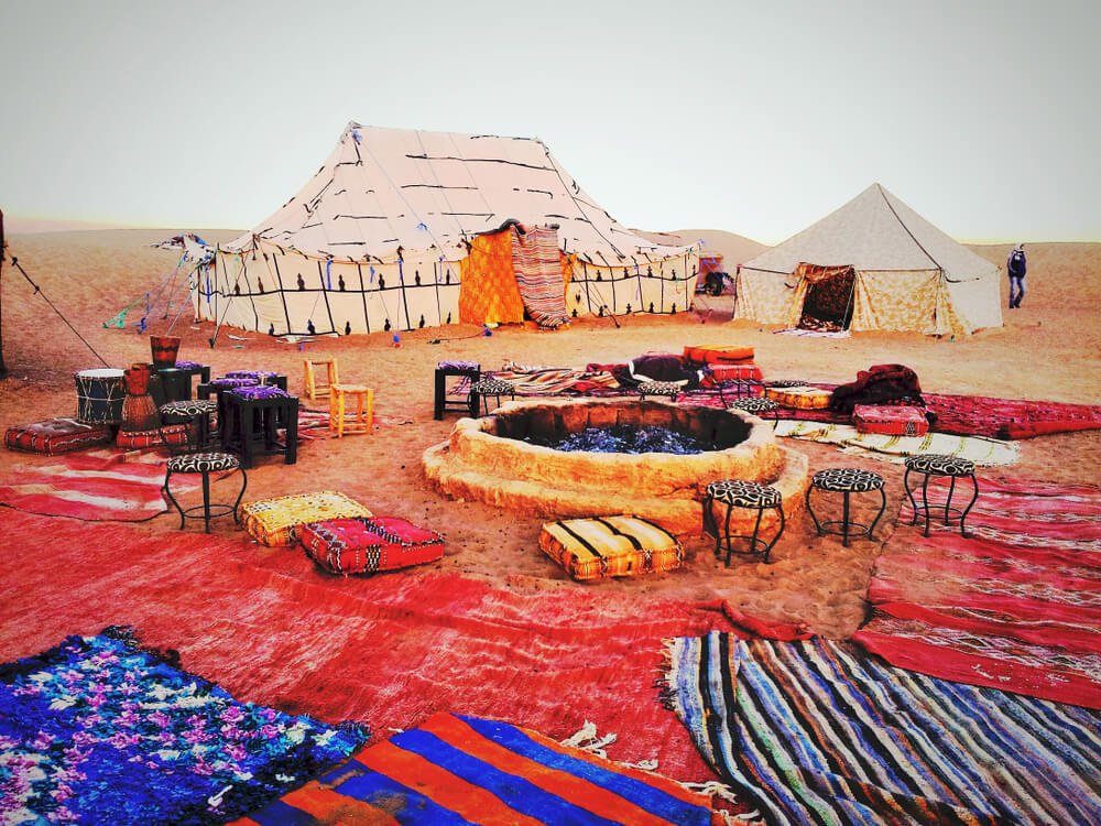 rugs surrounding a campfire and some makeshift tents in the Sahara